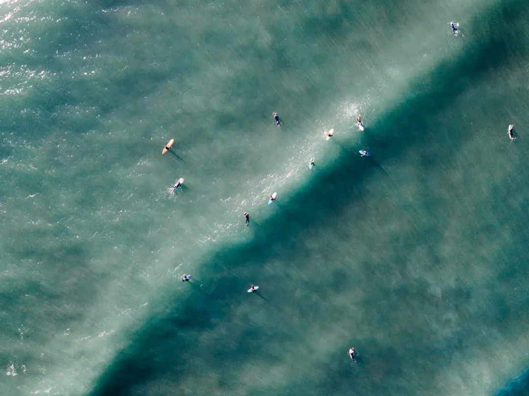 Aerial view of surfers in turquoise waters with visible wave patterns and white water